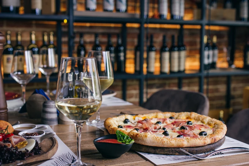 Pizza with prosciutto and lives with wine in restaurant